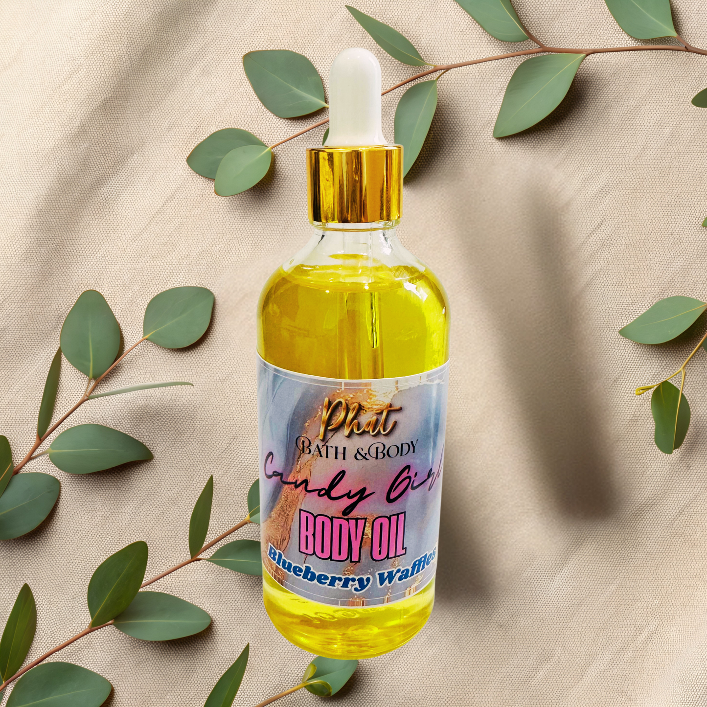 Bottle of body oil with a colorful label on a beige fabric background with green leaves.