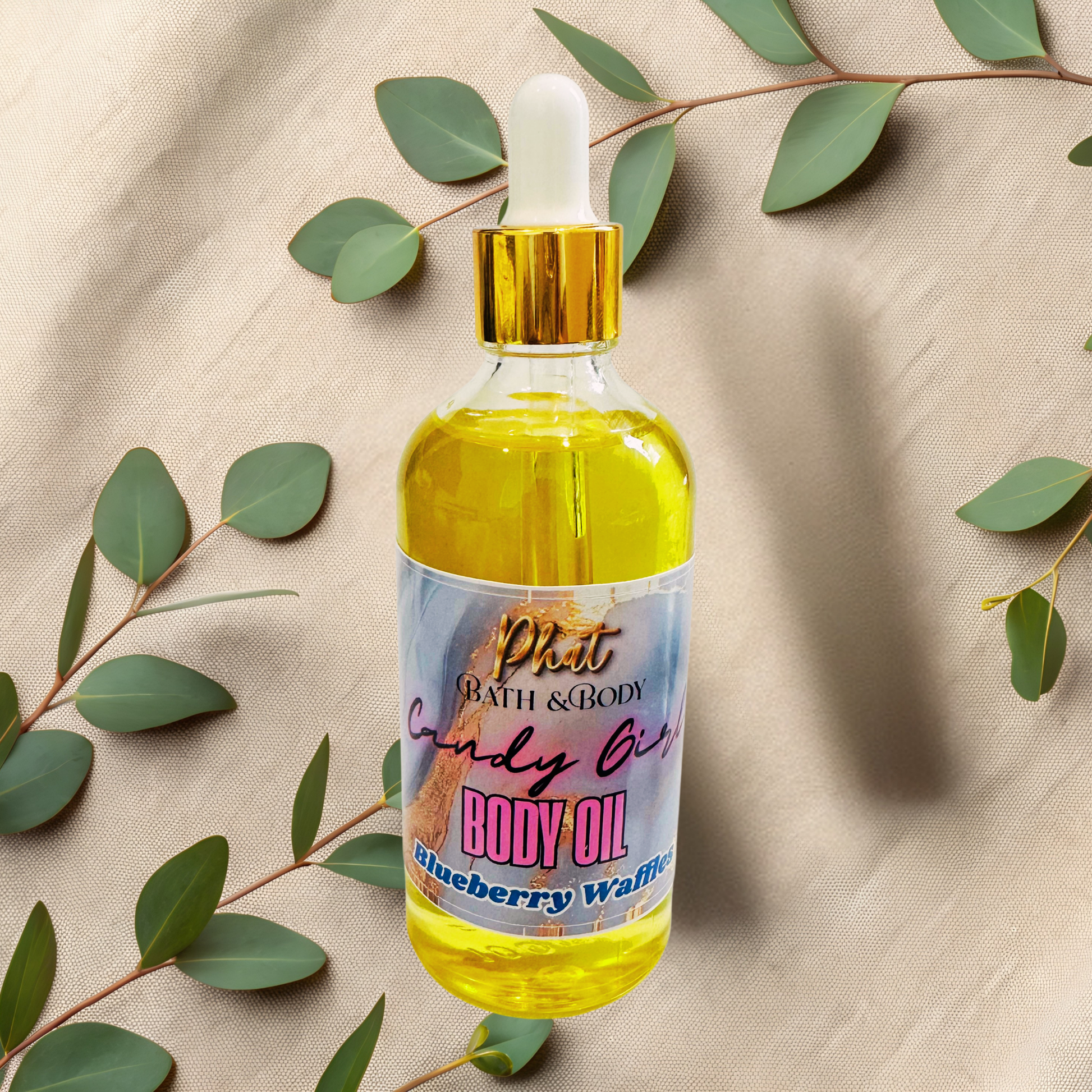 Bottle of body oil with a colorful label on a beige fabric background with green leaves.