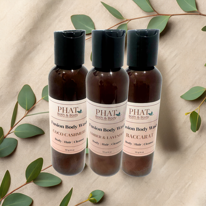 Three bottles of PHAT Bath & Body Fusion Body Wash on a beige fabric background with green leaves.