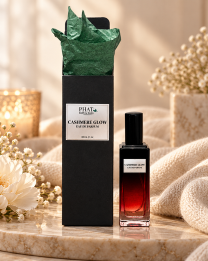 Cashmere Glow women’s Eau de Parfum bottle with black gift box and green tissue in a warm cashmere-inspired setting.