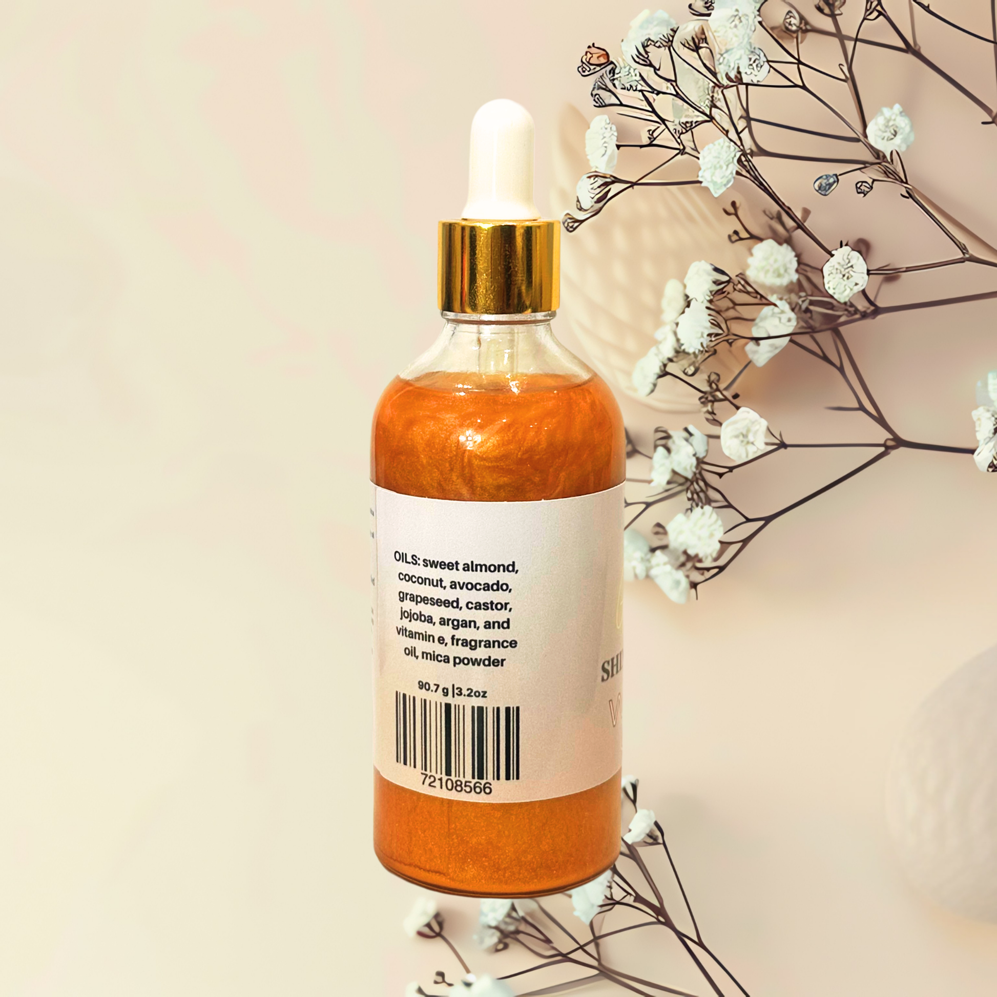 Bottle of gold liquid with a dropper on a beige background with white flowers.