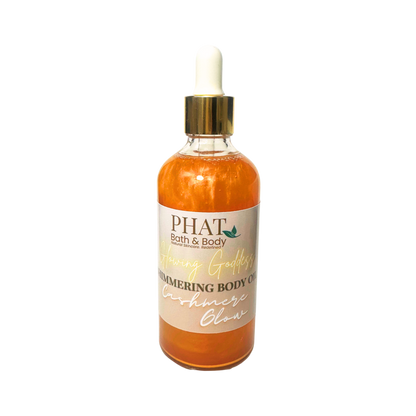 Gold bottle of 'Glowing' shimmering body oil by Phat Bath & Body on a white background