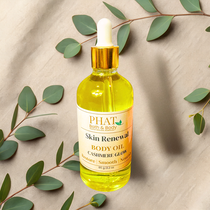 Bottle of PHAT Bath & Body Skin Renewal Body Oil with a dropper on a beige fabric background with green leaves.