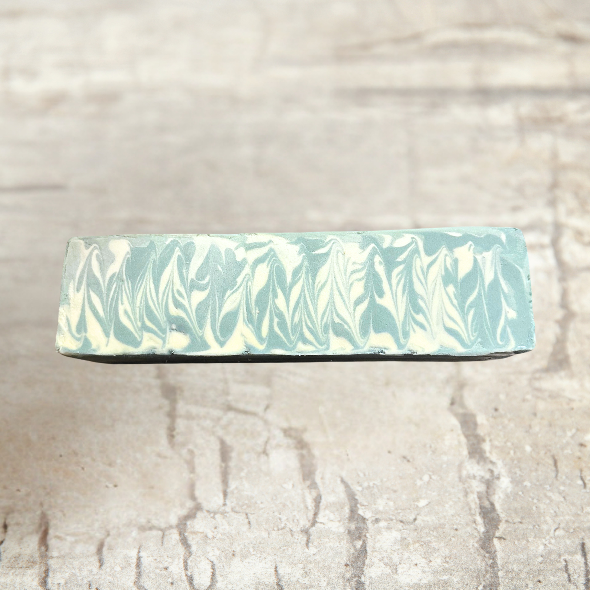 Marbled soap block with green and white pattern on a textured beige background