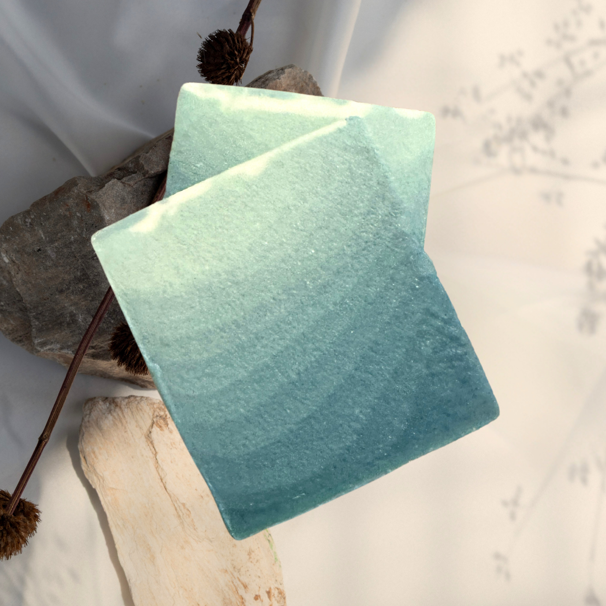Two green soap bars on a white background with natural elements.