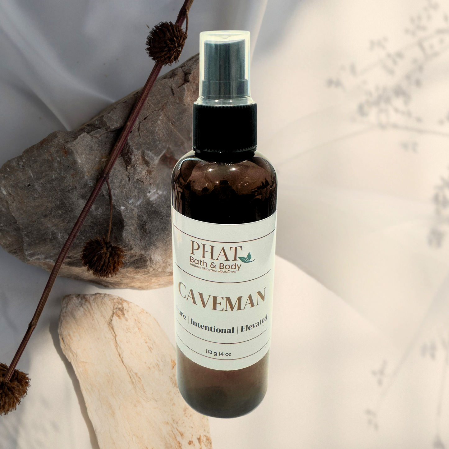 Bottle of 'Caveman' spray from Phat Bath & Body on a neutral background with decorative elements.