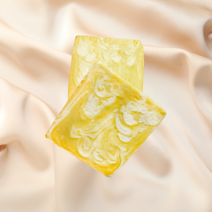 Yellow soap bar with white swirls on a beige fabric background