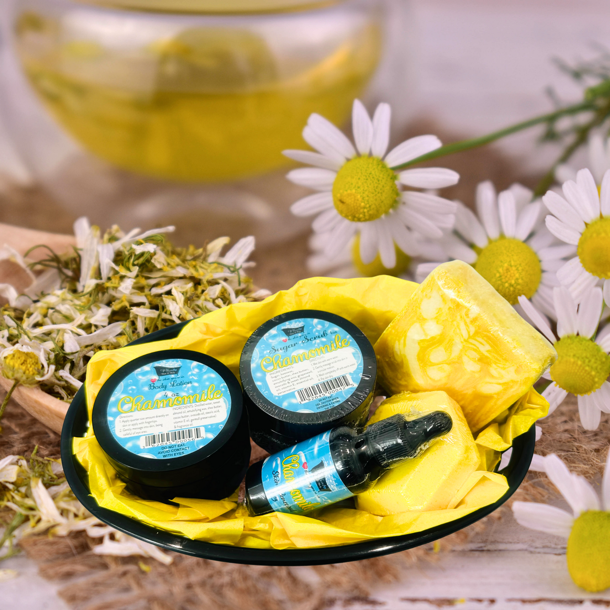Three small containers with labels and a dropper bottle on a yellow cloth, surrounded by daisies and a teacup.