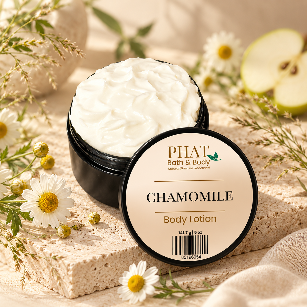 Phat Bath & Body Chamomile 5 oz Body Lotion in an open black jar with labeled lid, styled with chamomile flowers, green apple, soft botanicals, and warm natural stone.