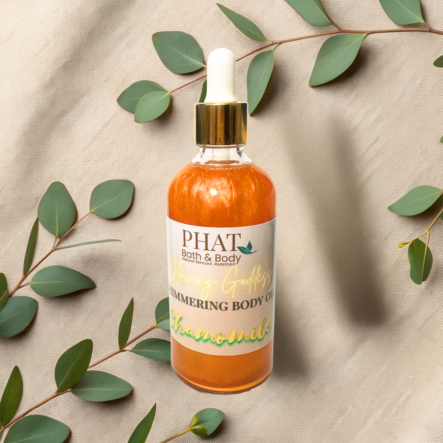 Bottle of PHAT Bath & Body chamomile body oil with a dropper on a beige fabric background with green leaves.