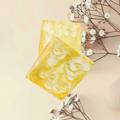 Yellow soap bar with white swirls on a light pink background with white flowers.
