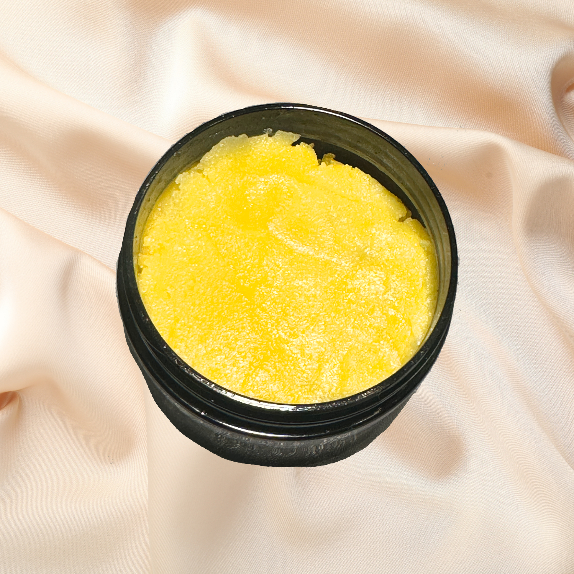 Black container with yellow scrub on a beige fabric background