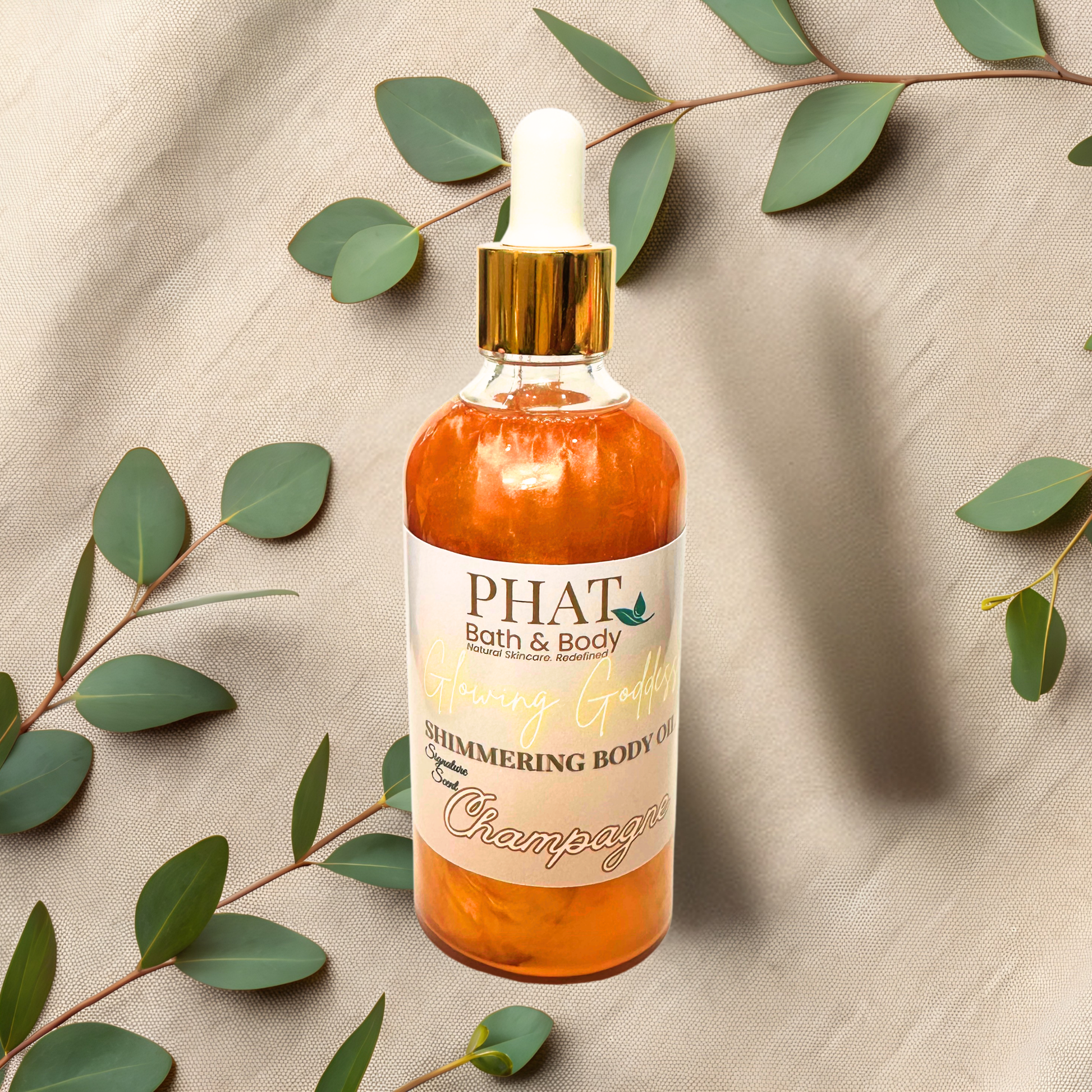 Bottle of 'PHAT Bath & Body' shimmering body oil with a dropper on a beige fabric background with green leaves.