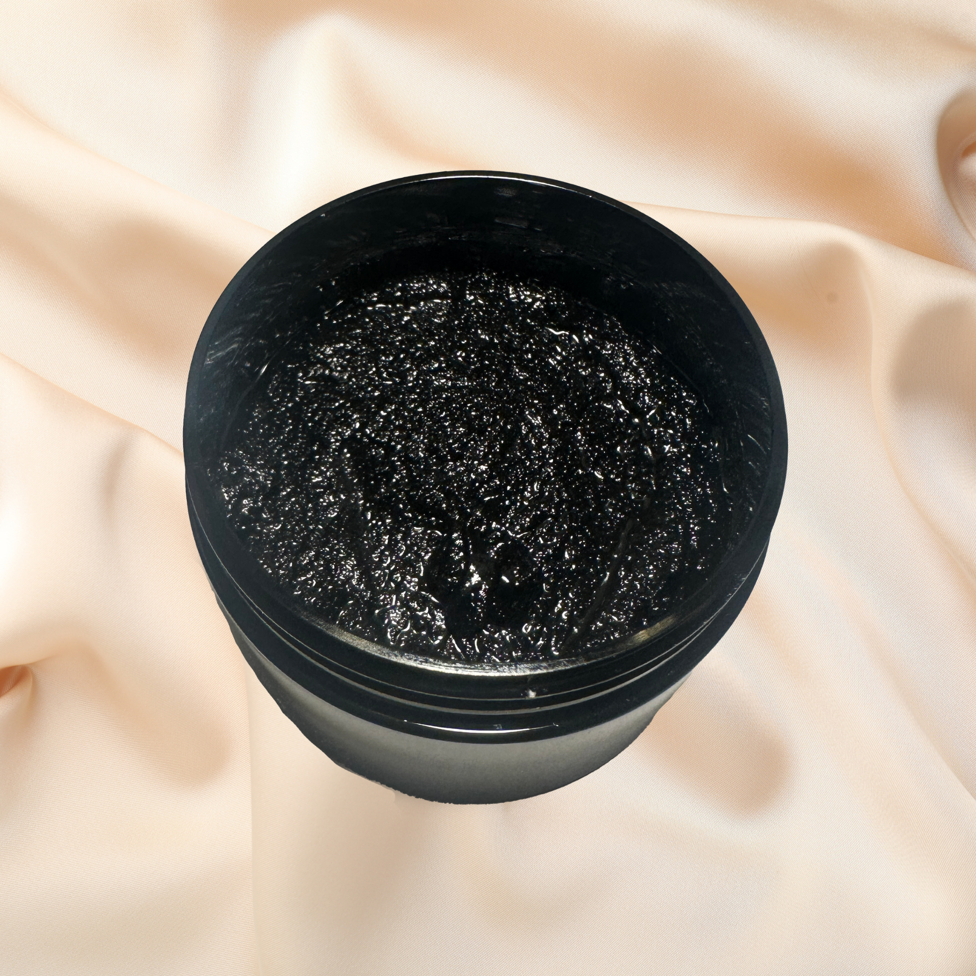 Black container of cosmetic scrub on a beige fabric background