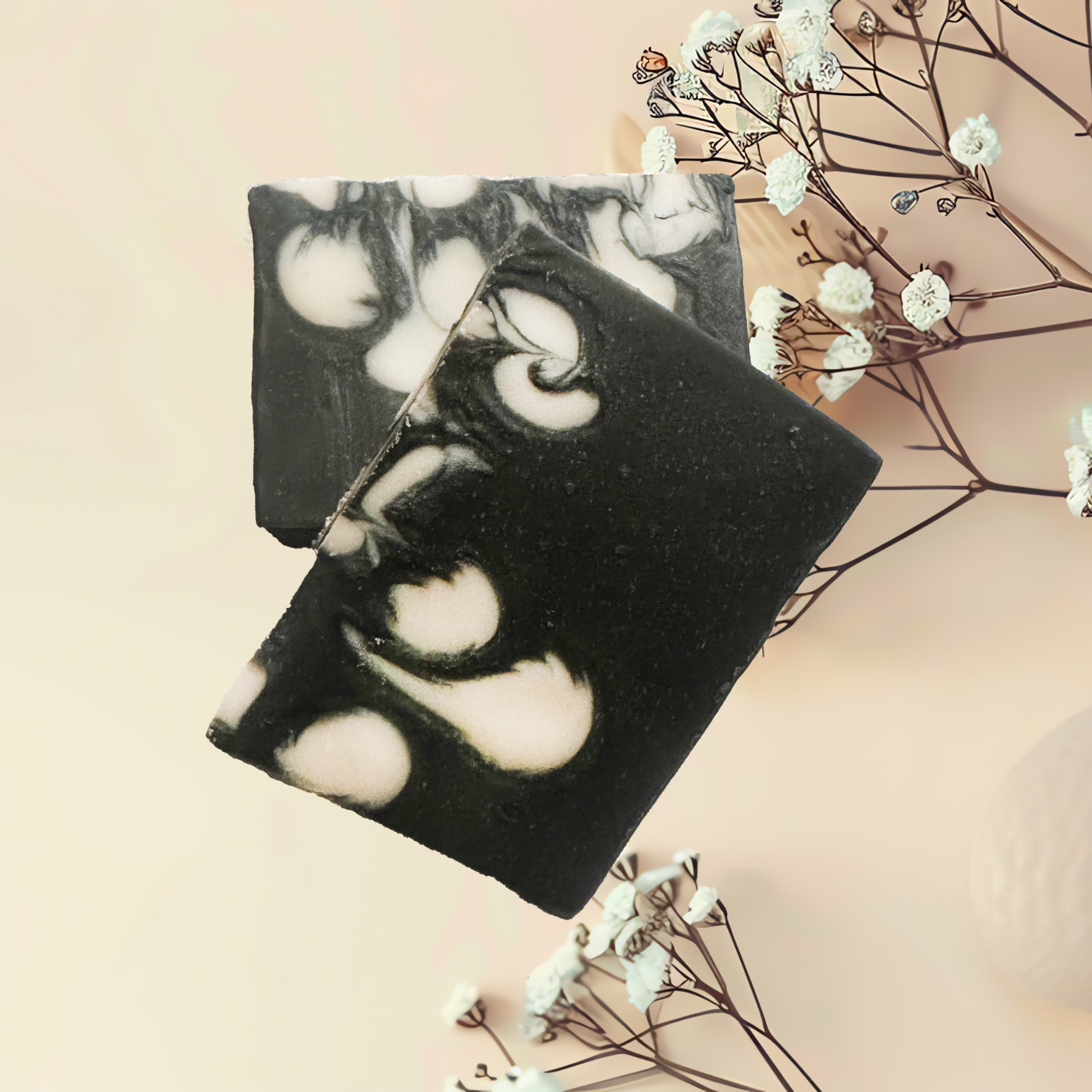 Black and white soap bars with floral elements on a soft pink background