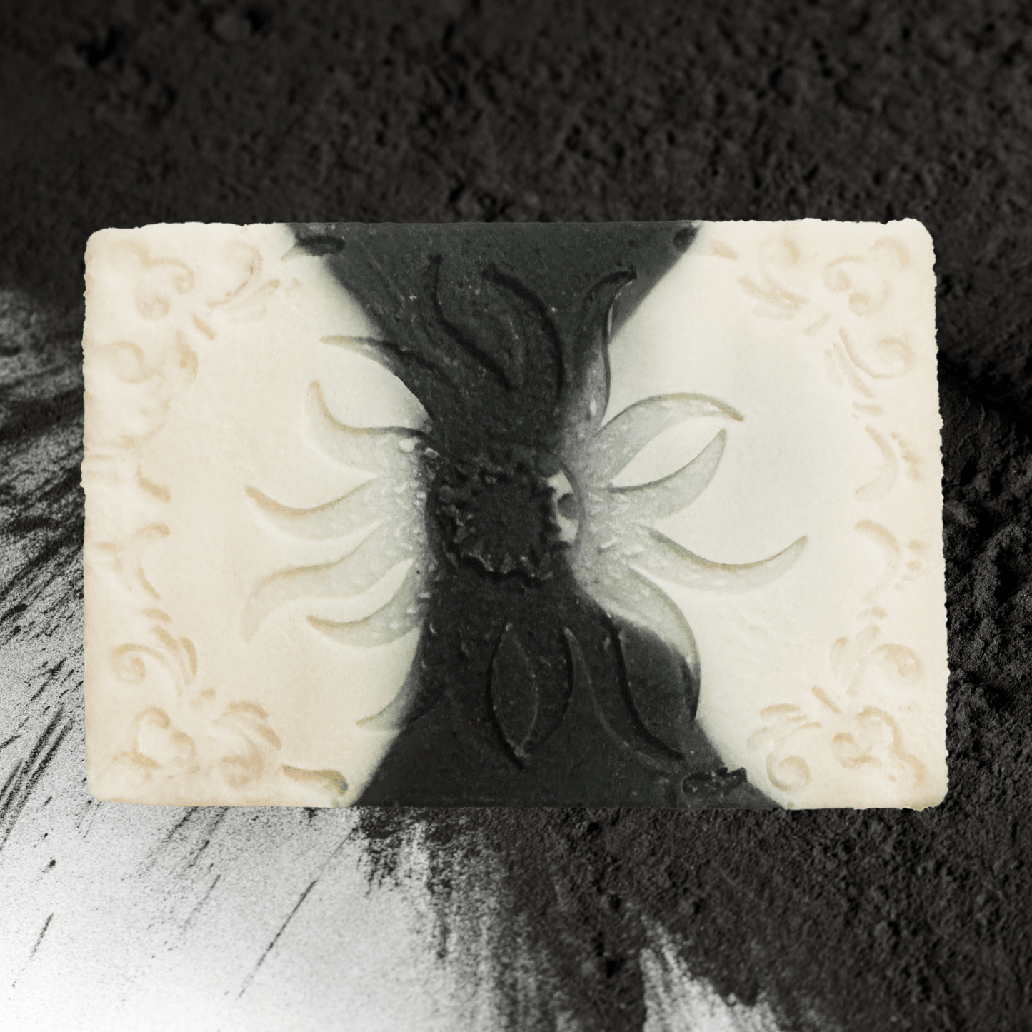 Decorative charcoal soap bar with embossed design on a textured black background