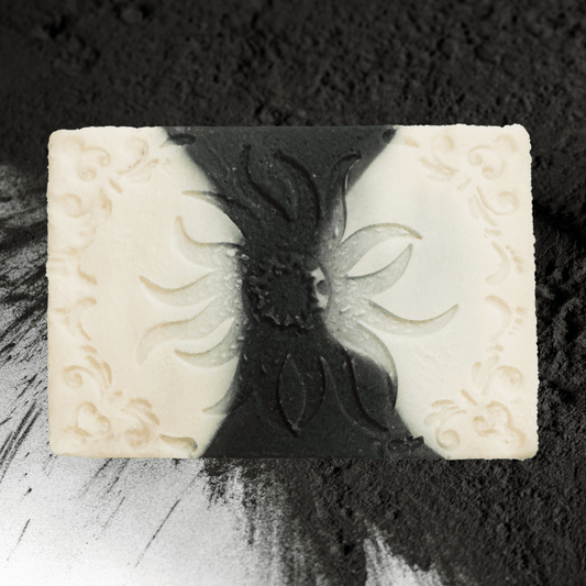 Decorative charcoal soap bar with embossed design on a textured black background