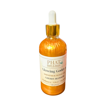 Orange bottle of 'Glowing Goddess' shimmer body oil by Phat Bath & Body on a white background