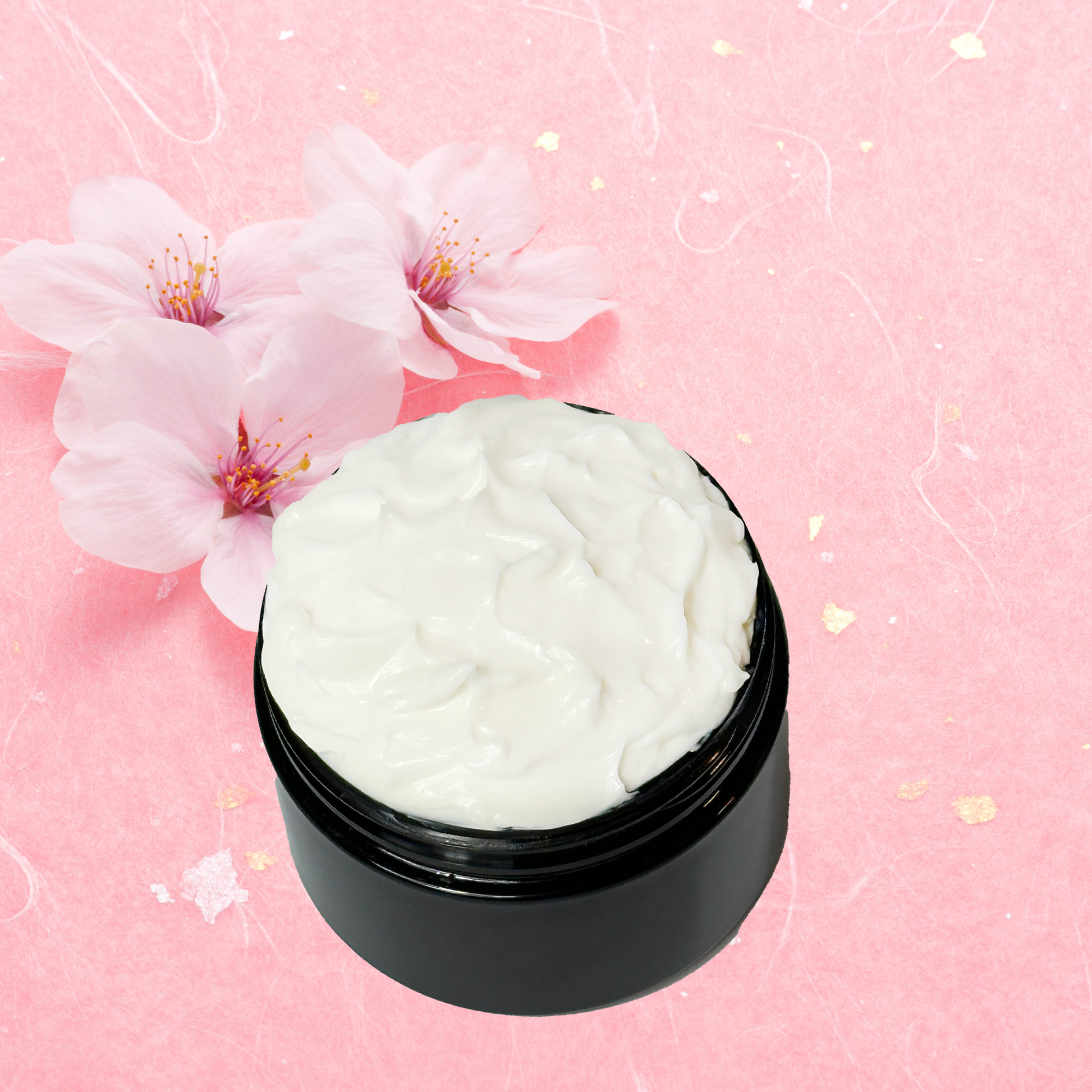 Black jar of white body cream with cherry blossoms on a pink background