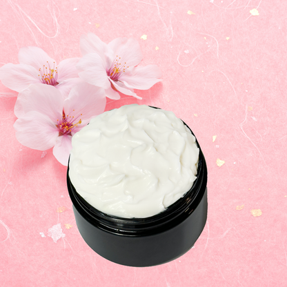 Black jar of white body cream with cherry blossoms on a pink background