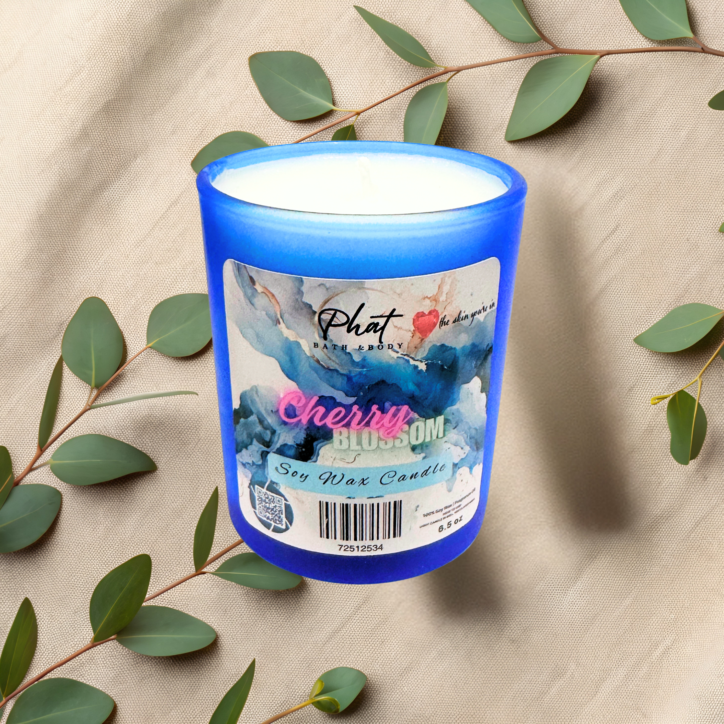 Blue candle with a label on a beige fabric background with green leaves