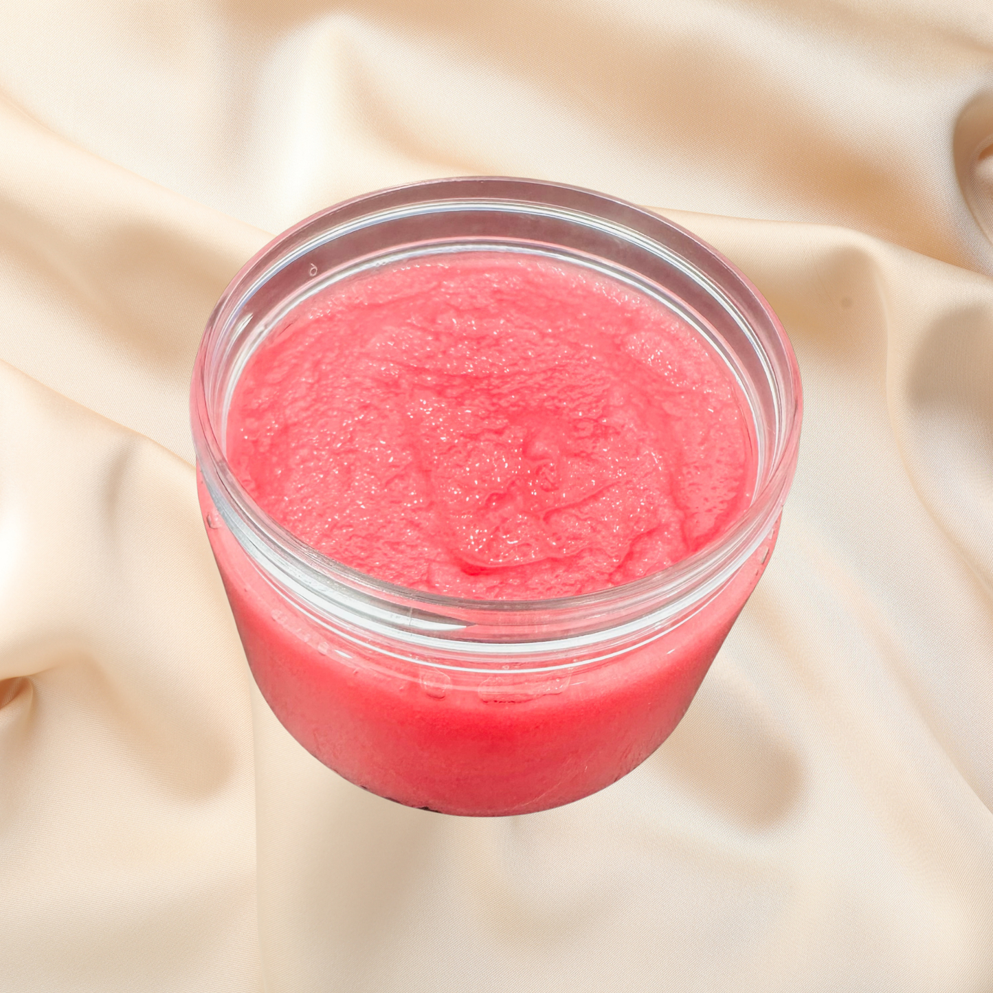 Jar of pink scrub on a beige fabric background