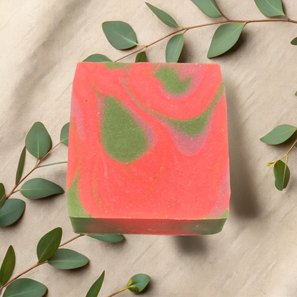 Bar of pink and green soap with eucalyptus leaves on a beige fabric background