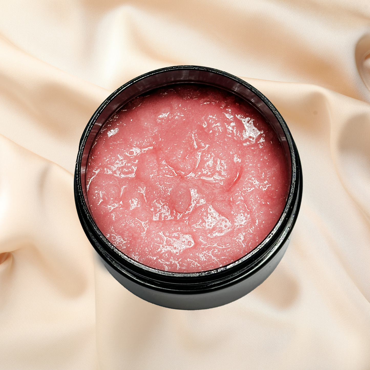 Pink scrub in a black container on a beige fabric background