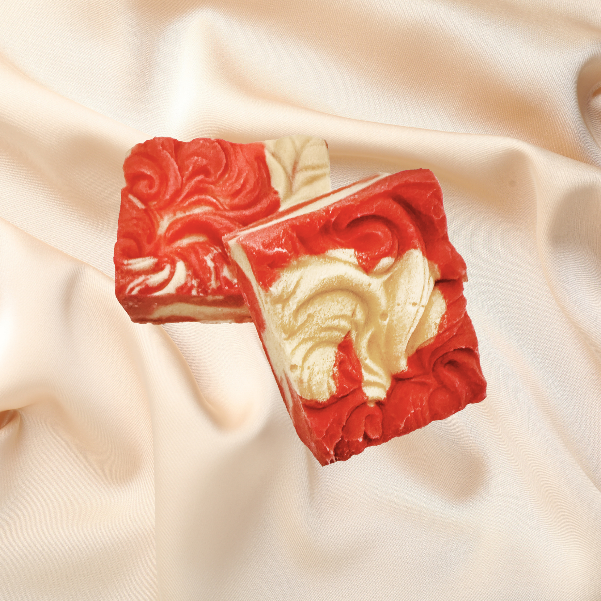 Two red and gold soap bars with intricate designs on a beige fabric background