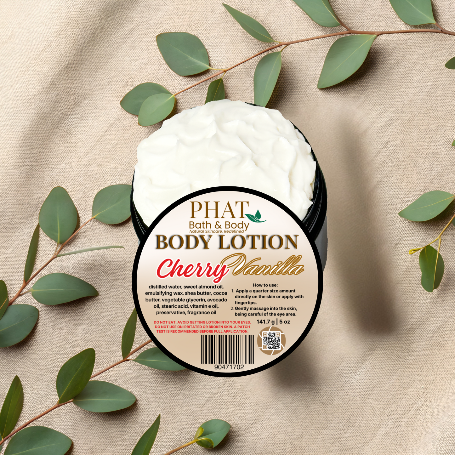 Body lotion container labeled 'Cherry Vanilla' by Phat Bath & Body on a beige fabric background with green leaves.