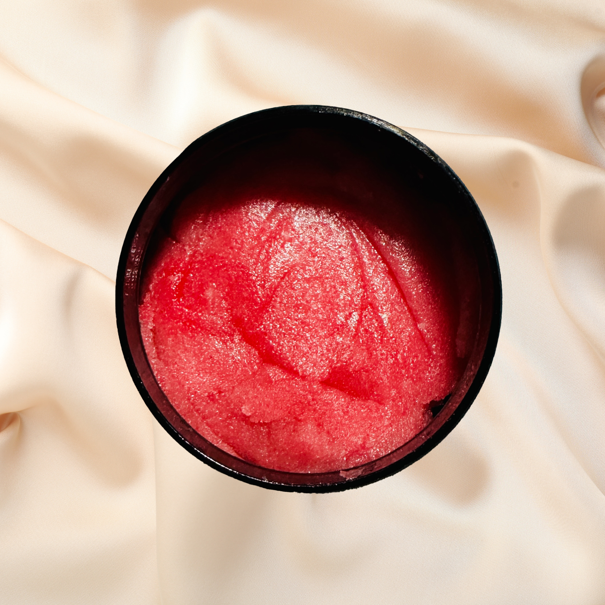 Red scrub in a black container on a beige fabric background