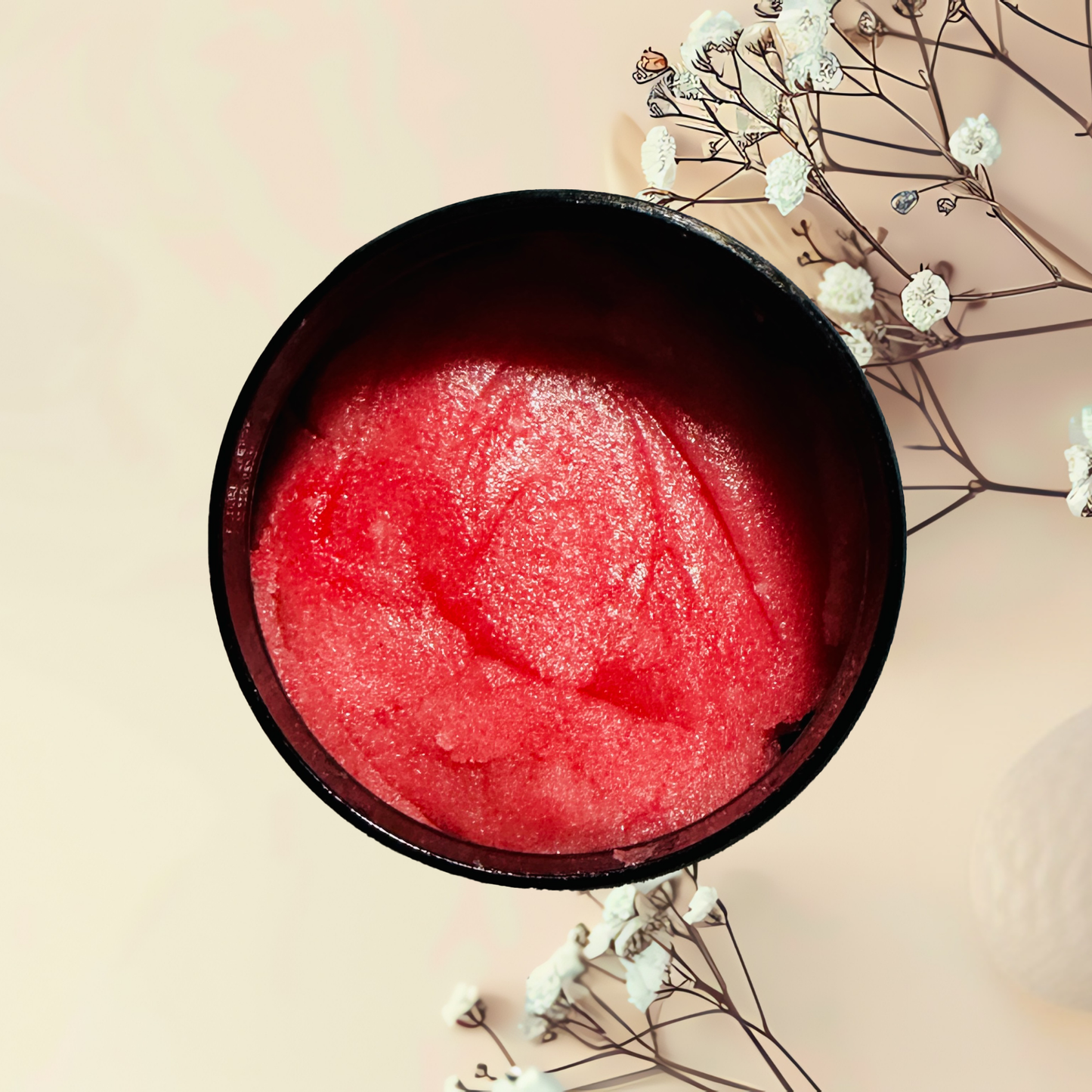 Red scrub in a black bowl with white flowers on a light background