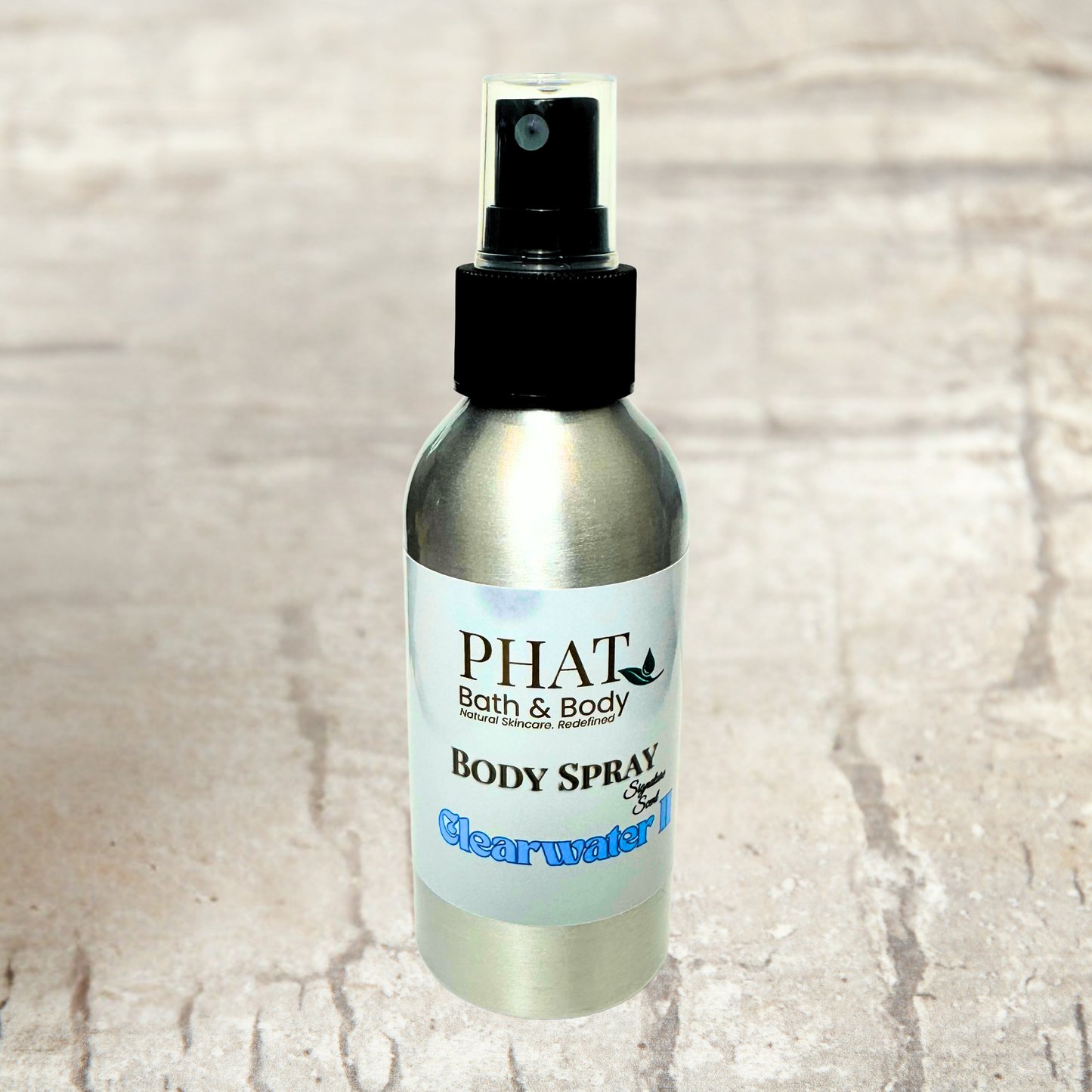 Body spray bottle labeled 'PHAT Bath & Body' on a textured beige background