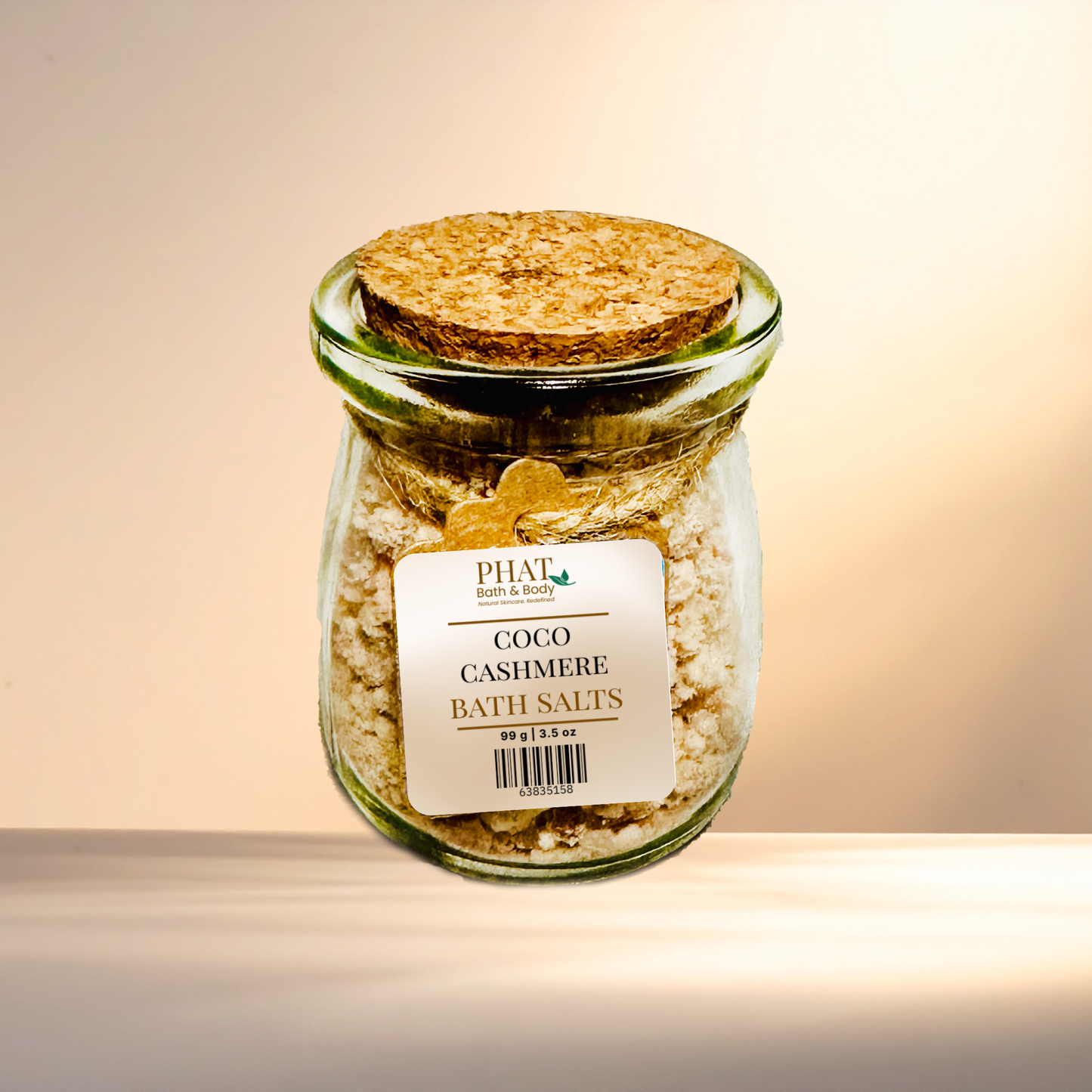 Jar of Coco Cashmere Bath Salts with a cork lid on a gradient background