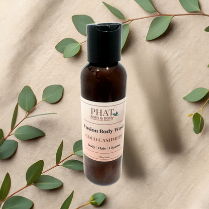 Bottle of PHAT Bath & Body Fusion Body Wash with eucalyptus leaves on a beige fabric background