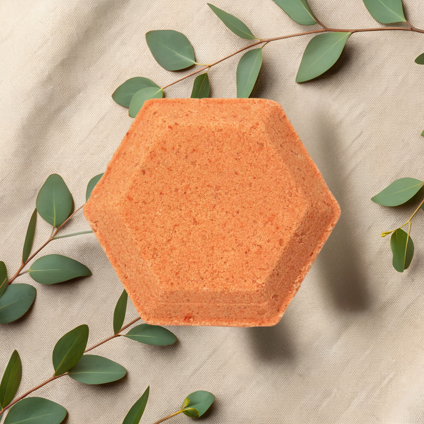 Hexagonal orange steamer with green leaves on a beige fabric background
