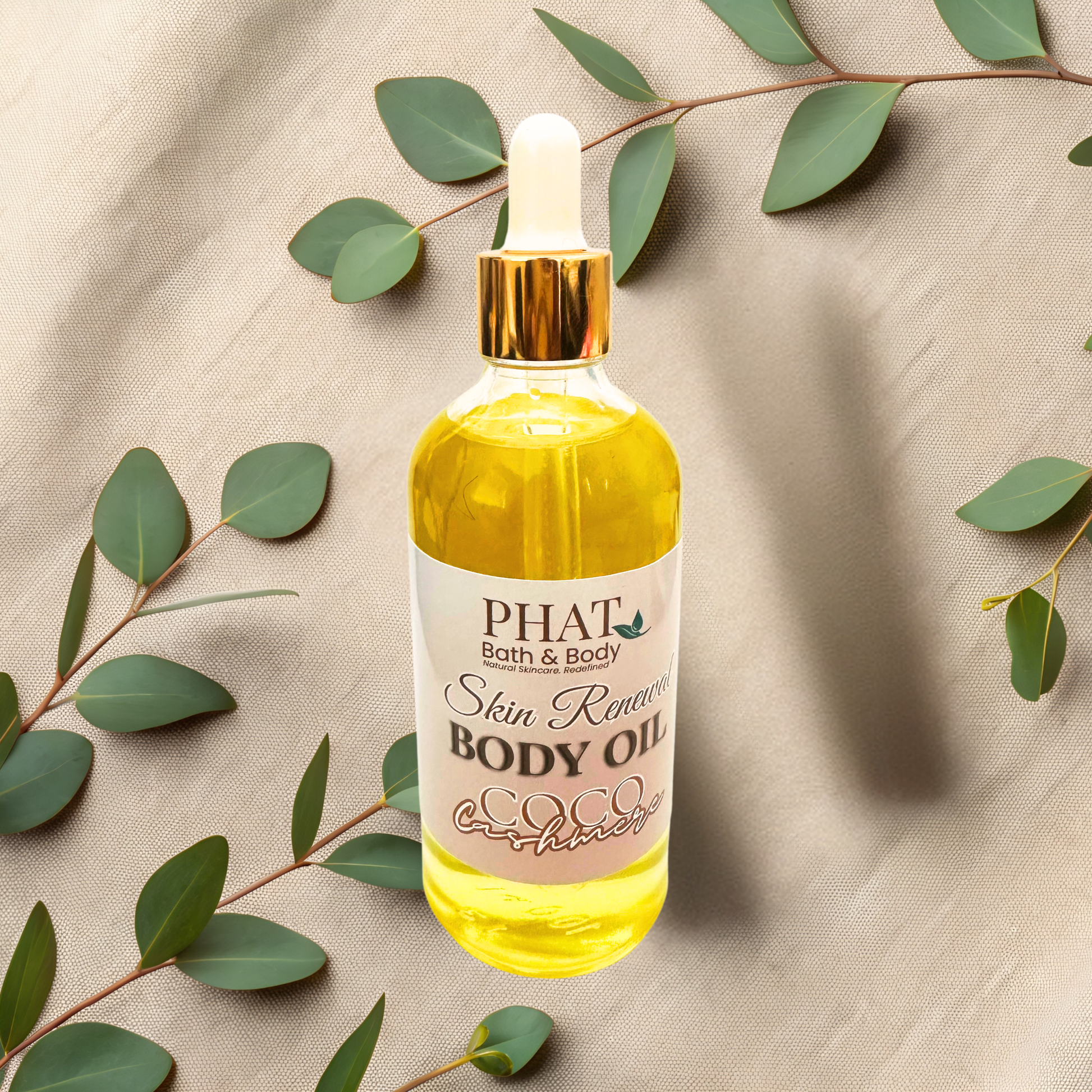 Bottle of Phat Bath & Body body oil with green leaves on a beige fabric background