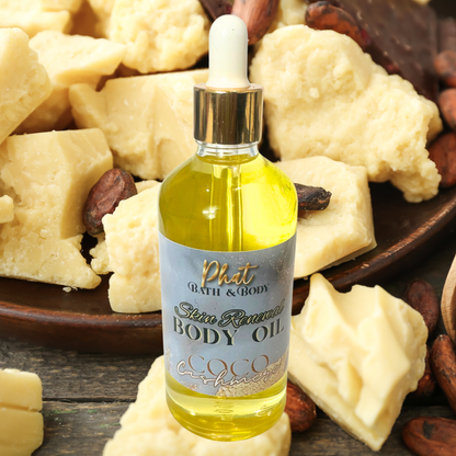 Body oil bottle with a dropper labeled 'Phat Bath & Body' surrounded by cocoa butter and nuts on a wooden surface.