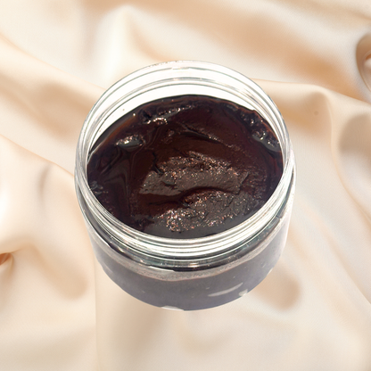 Jar of dark brown scrub on a beige fabric background