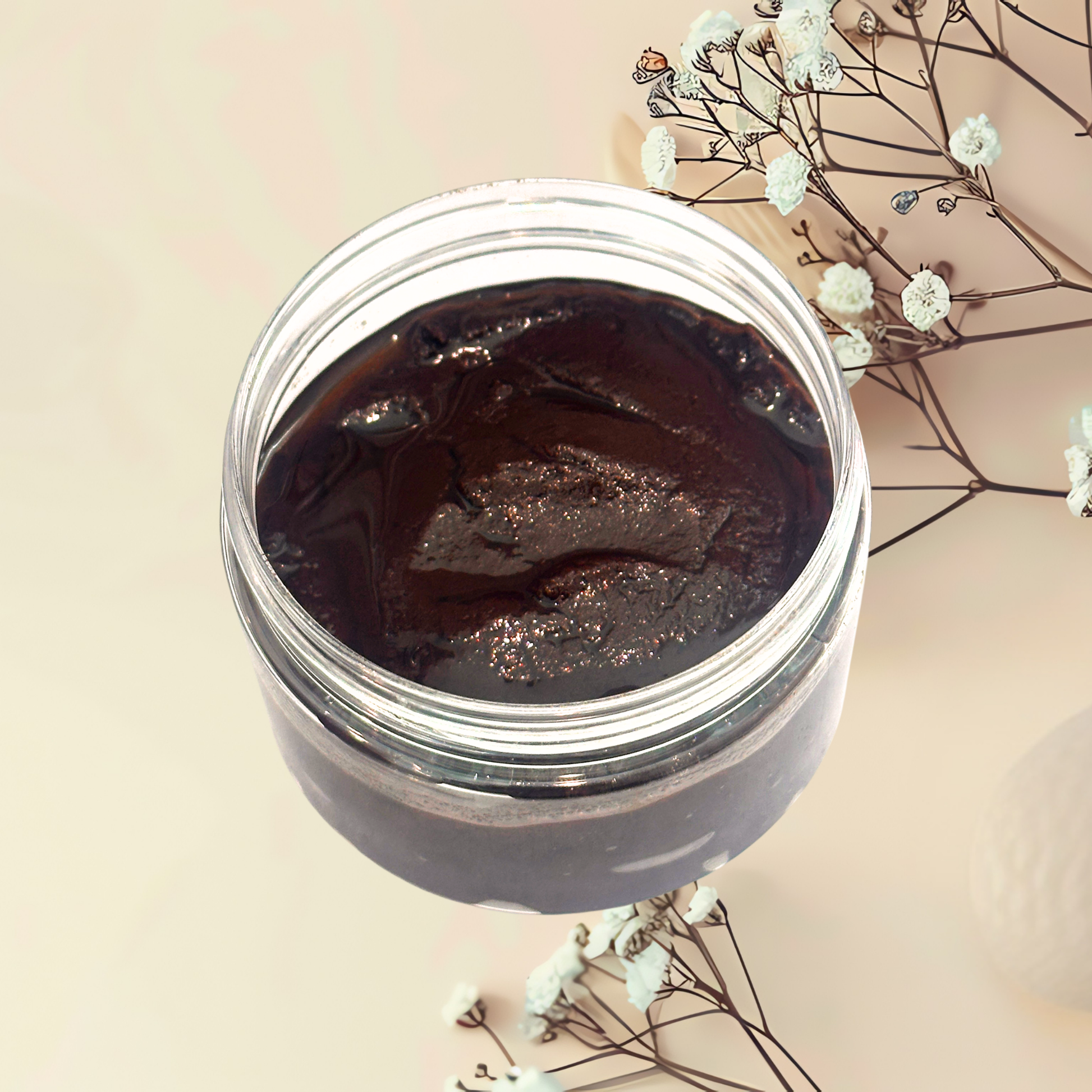 Jar of dark brown scrub with flowers on a light background