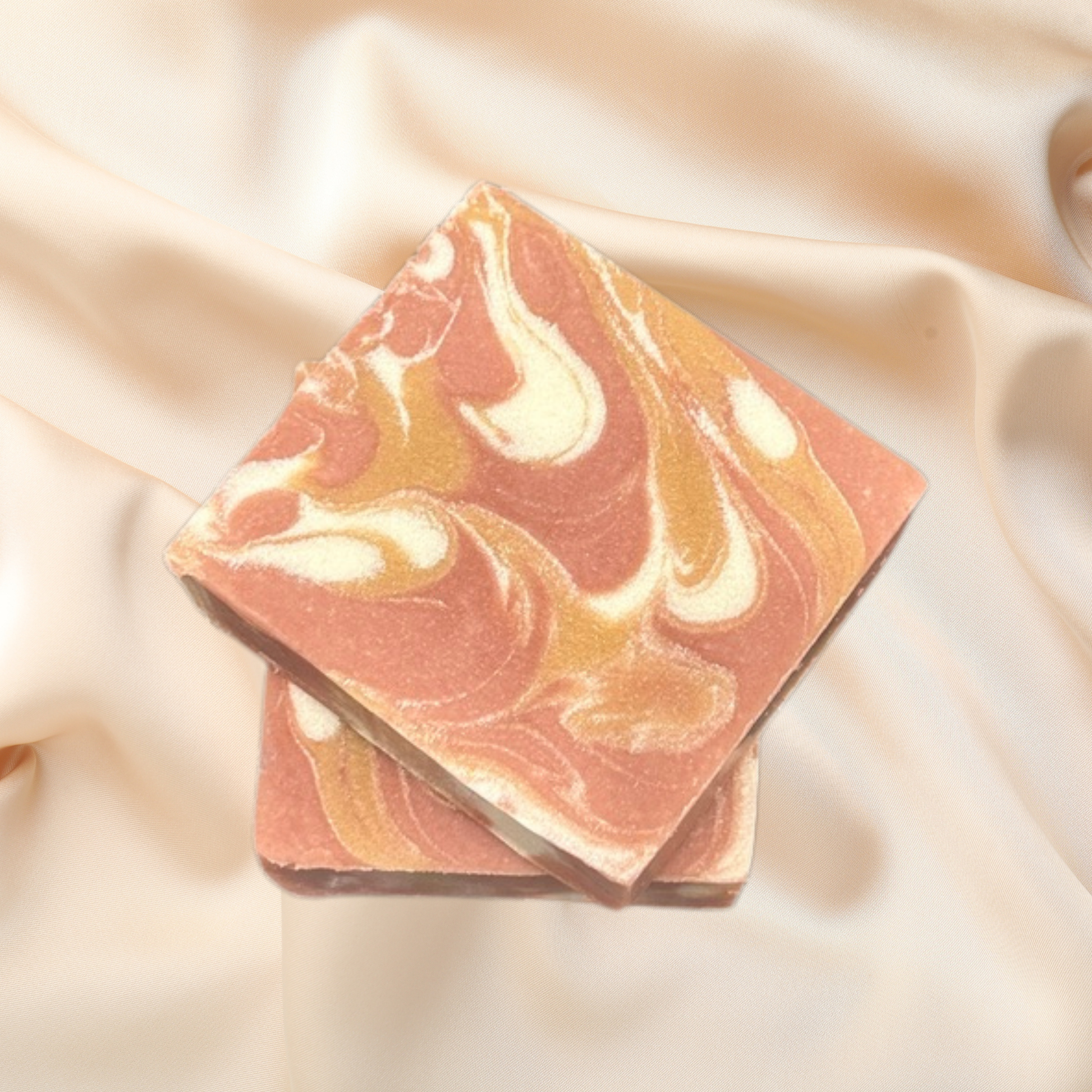 Marbled soap bar with pink and gold swatches on a beige fabric background