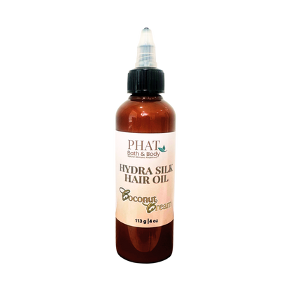 A bottle of PHAT Bath & Body  Hydra Silk Hair Oil in Coconut Cream scent, featuring an amber brown bottle, black cap, and a cream-colored label.