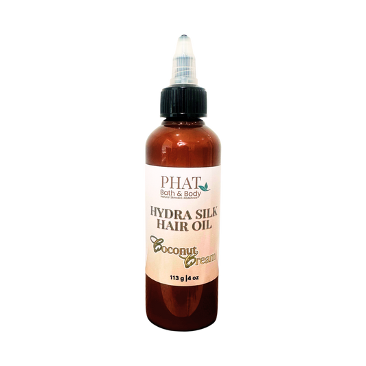 A bottle of PHAT Bath & Body  Hydra Silk Hair Oil in Coconut Cream scent, featuring an amber brown bottle, black cap, and a cream-colored label.