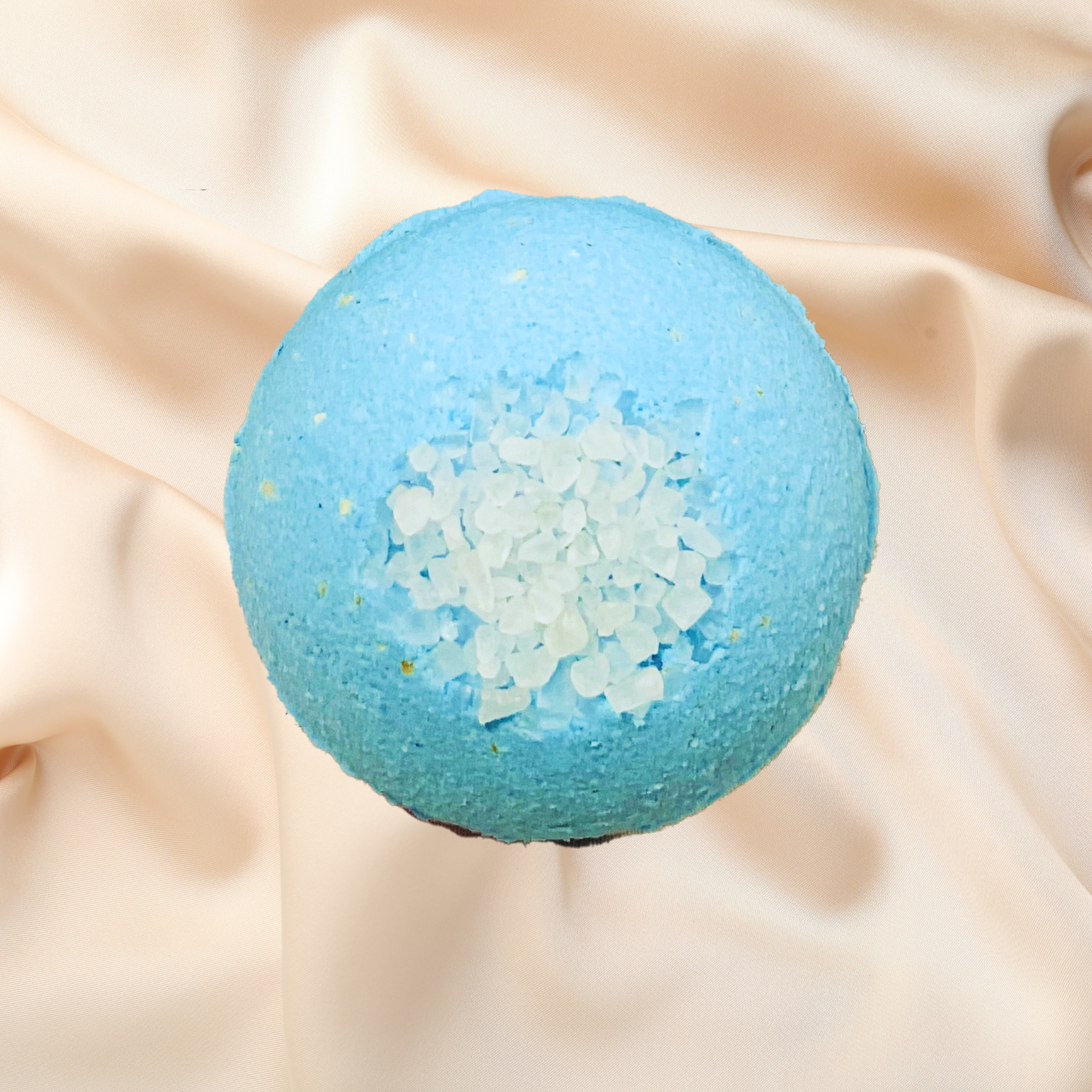 Blue bath bomb with sparkling texture on beige fabric