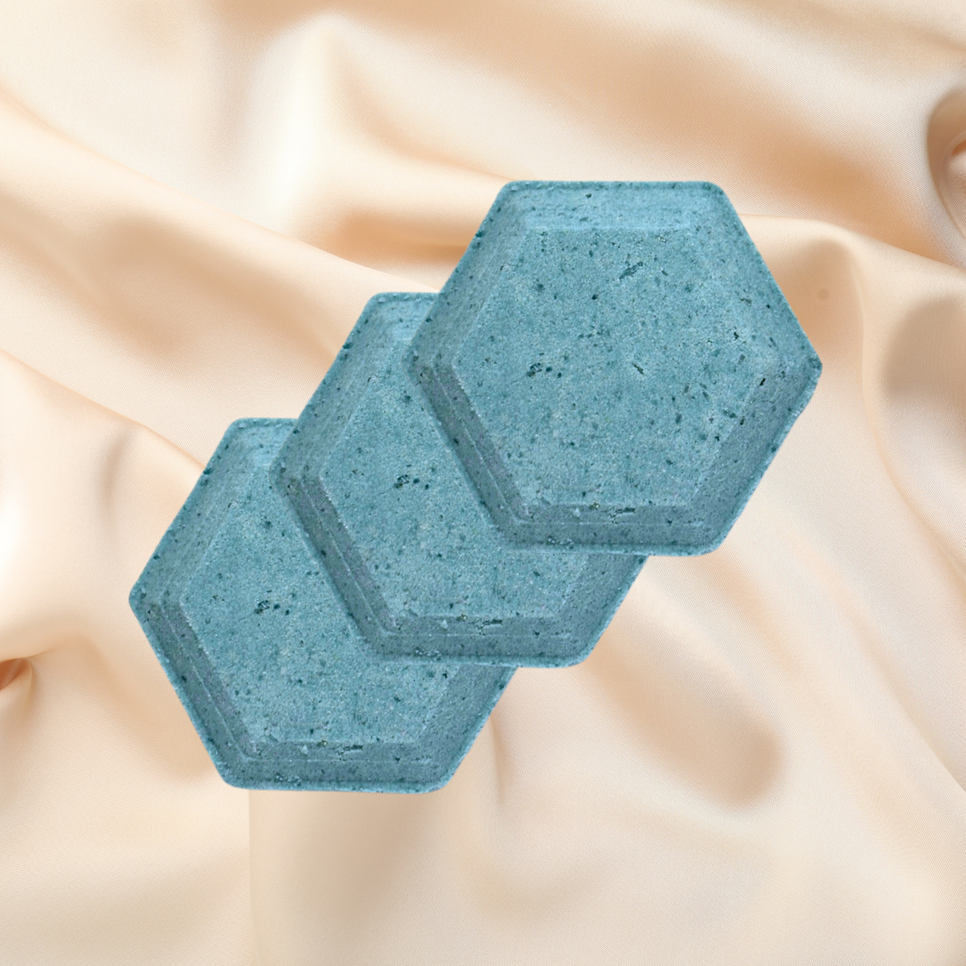 Two blue hexagonal shower bombs on a beige fabric background