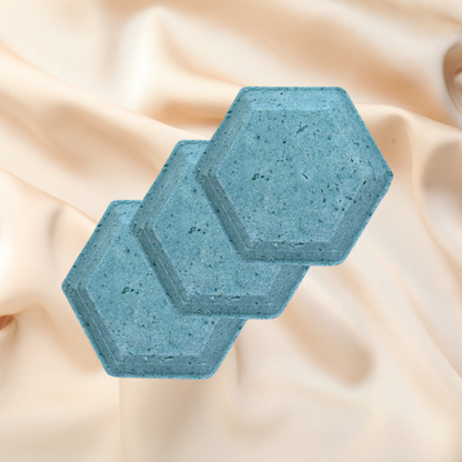 Two blue hexagonal shower bombs on a beige fabric background