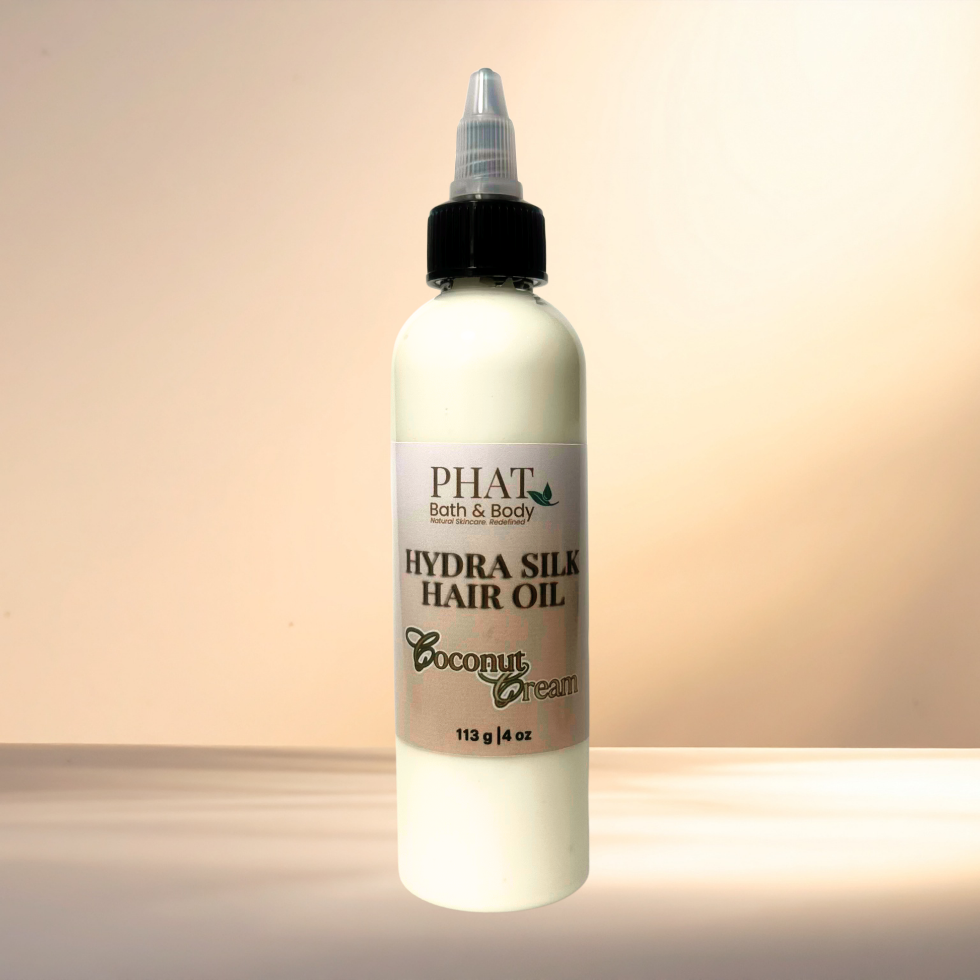 Bottle of PHAT Bath & Body Hydra Silk Hair Oil with coconut cream scent on a gradient background