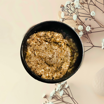 Brown sugar scrub in a black bowl with white flowers on a beige background