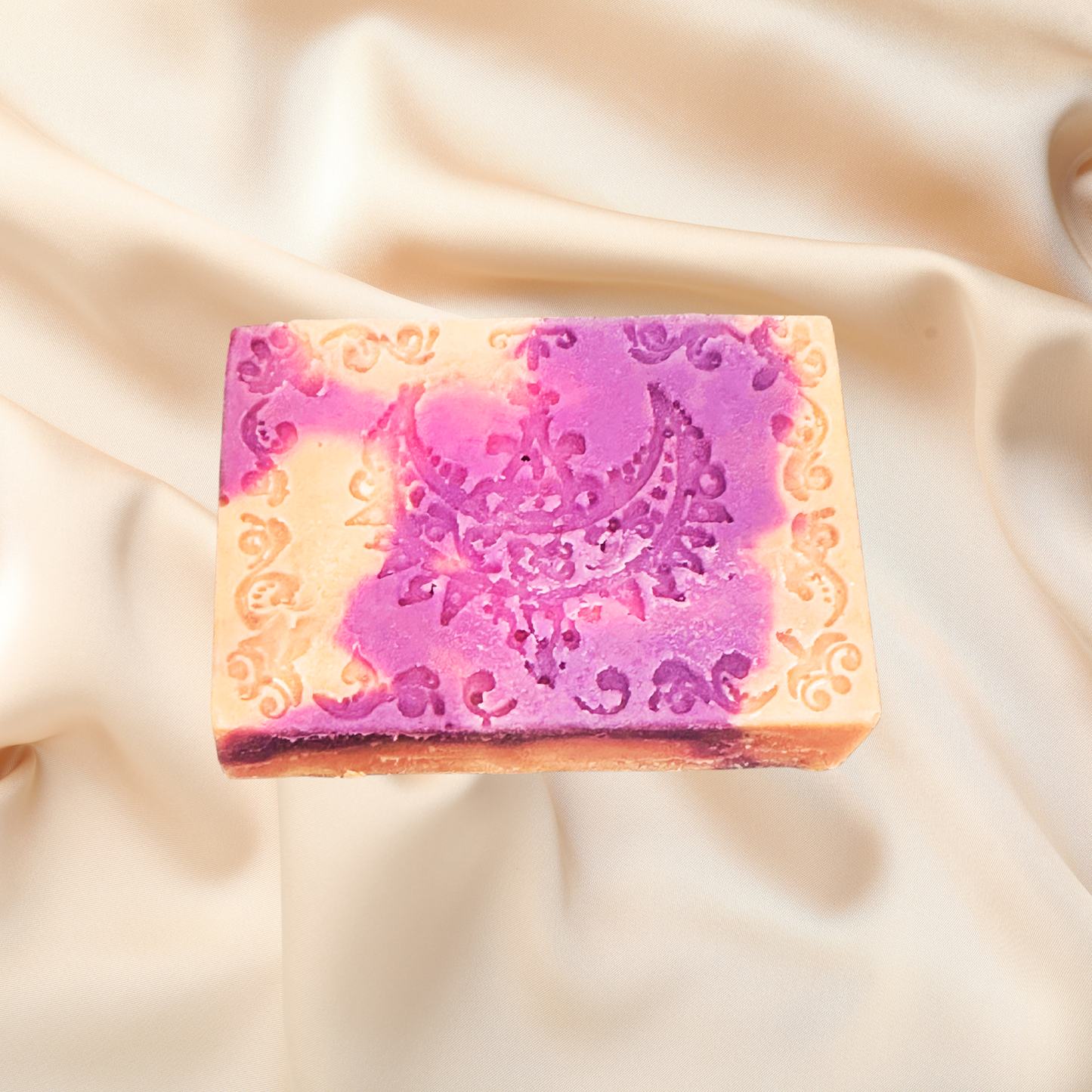 Decorative soap bar with intricate design on a soft fabric background
