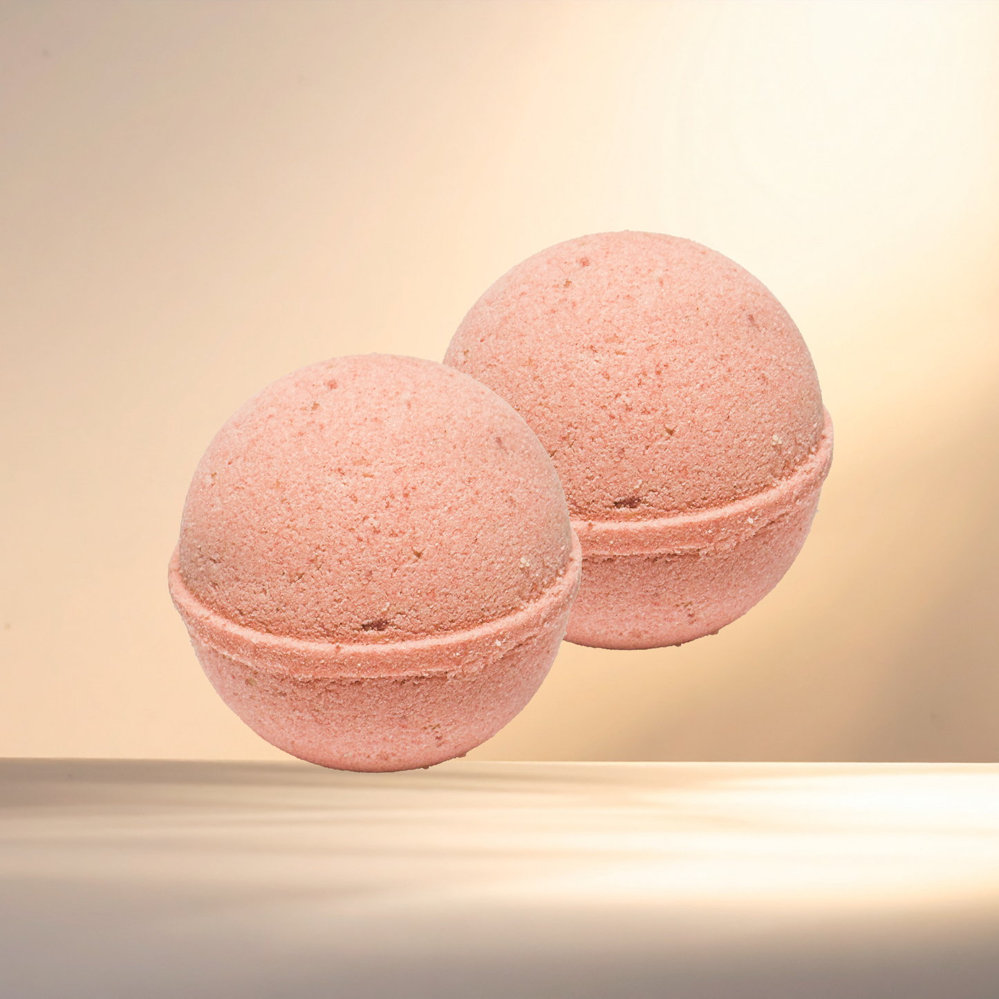 Two pink bath bombs on a beige background